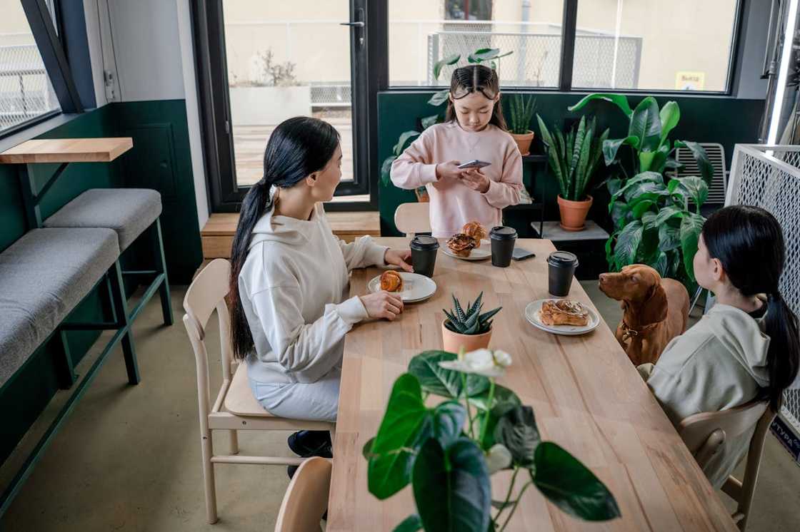 Three people sit around a table with pastries and coffee. Three people sit around a table with pastries and coffee.