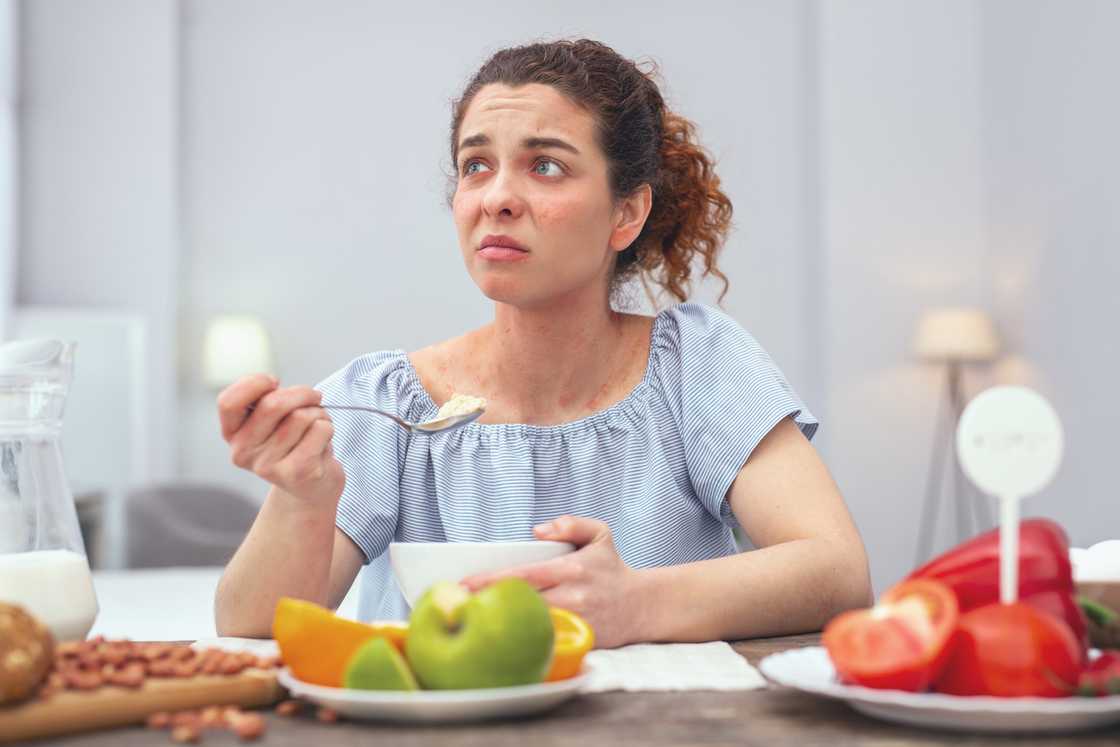 An angry woman shocked as she eats at a dinner table An angry woman shocked as she eats at a dinner table