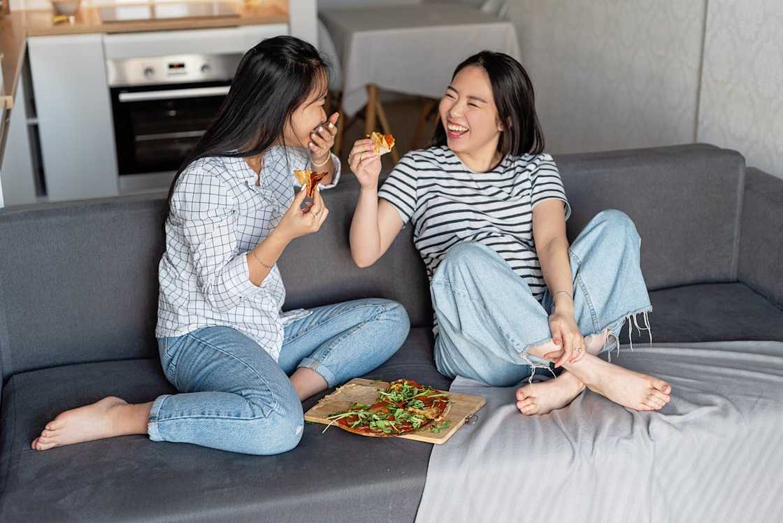 Two friends sit on the couch laughing together. Two friends sit on the couch laughing together.