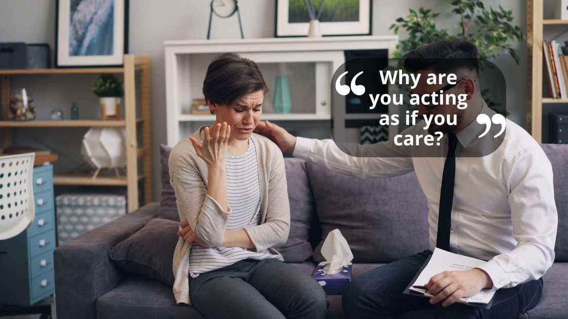 A distressed woman sits on a sofa as a man beside her offers support and holds paperwork. A distressed woman sits on a sofa as a man beside her offers support and holds paperwork.