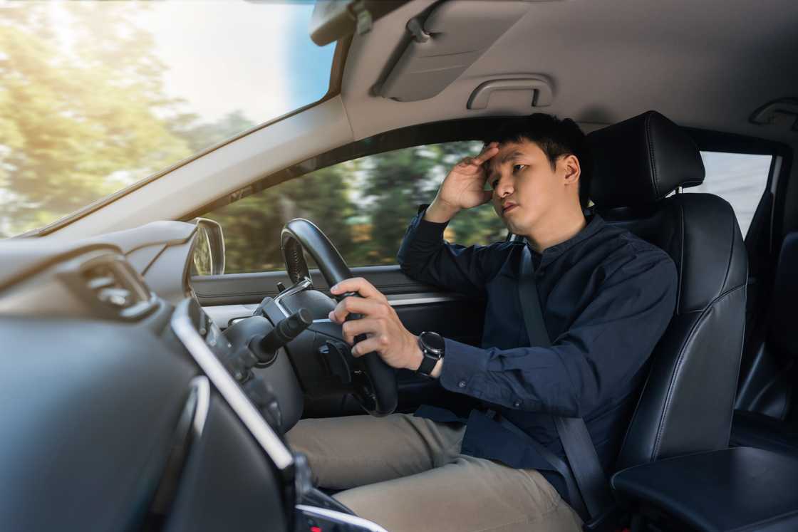 A stressed man driver sitting inside a car