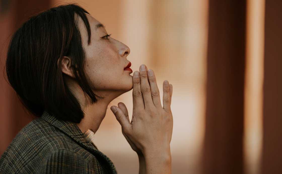 A woman prays quietly with her hands clasped.