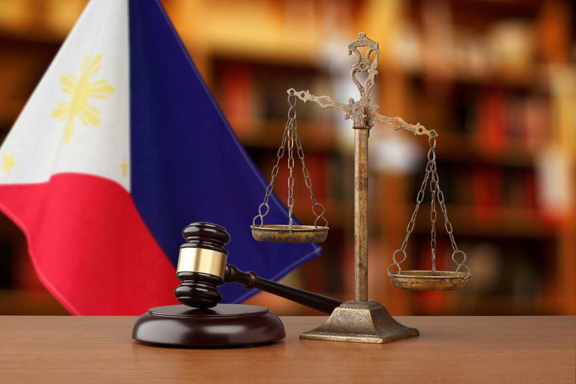 Gavel and justice scale set against the Philippine flag in a law-themed environment. Gavel and justice scale set against the Philippine flag in a law-themed environment.