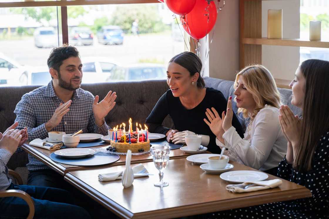 A group of people sit around a table celebrating a birthday.