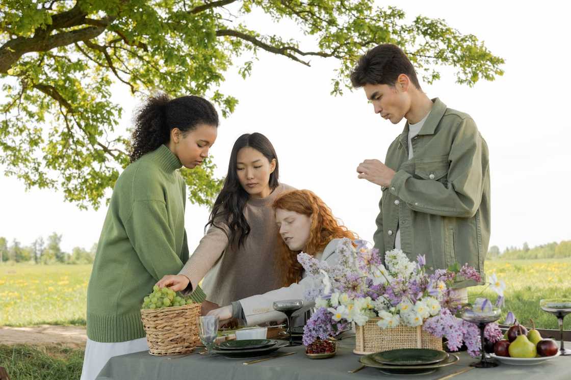 Four people gather around a table outdoors. Four people gather around a table outdoors.