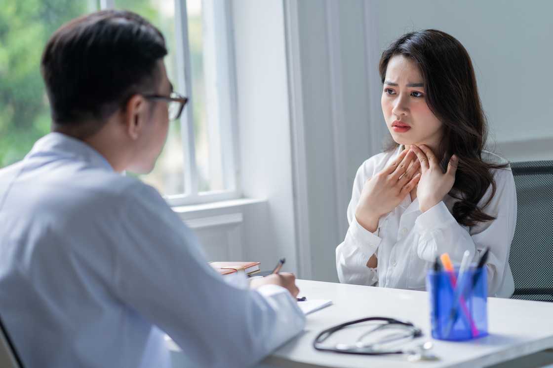 A woman consults a doctor about throat strain from overuse.