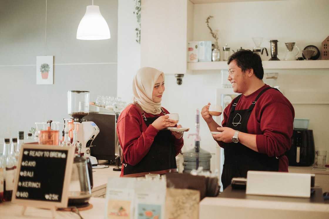 A couple laughs while filming a cooking video in their kitchen.