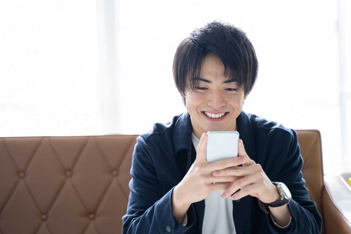 A smiling man reading good news in his phone smiling