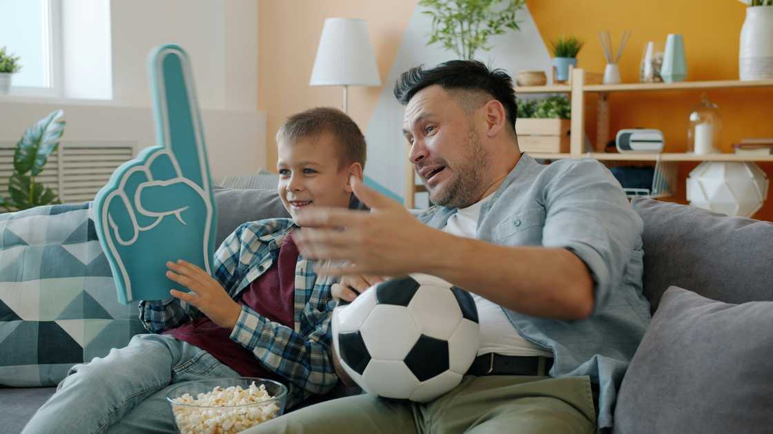 A teen watching football with his father
