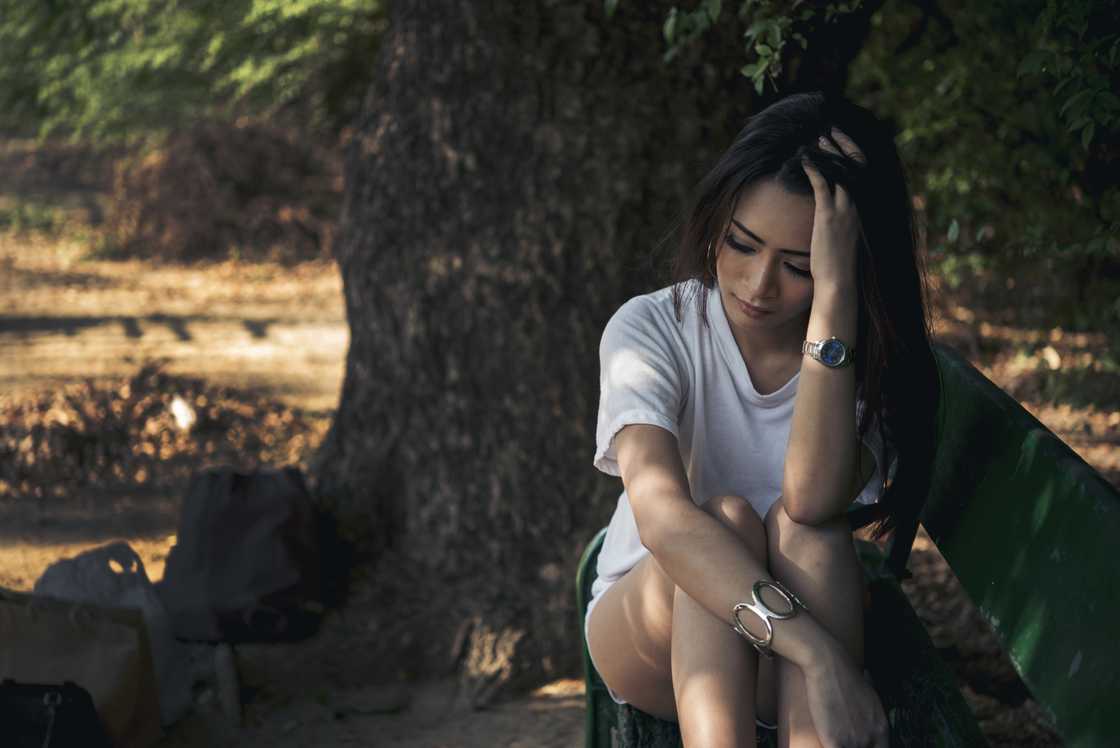 A worried woman sitting under a tree A worried woman sitting under a tree