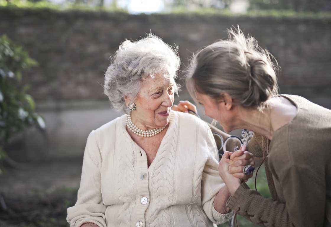 Elderly woman and her daughter sharing a warm outdoor moment.