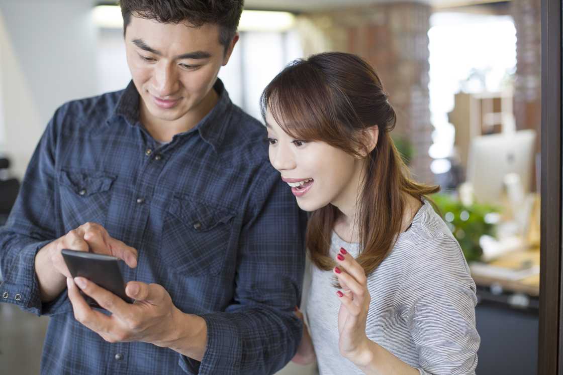 a man showing a woman good news on phone a man showing a woman good news on phone