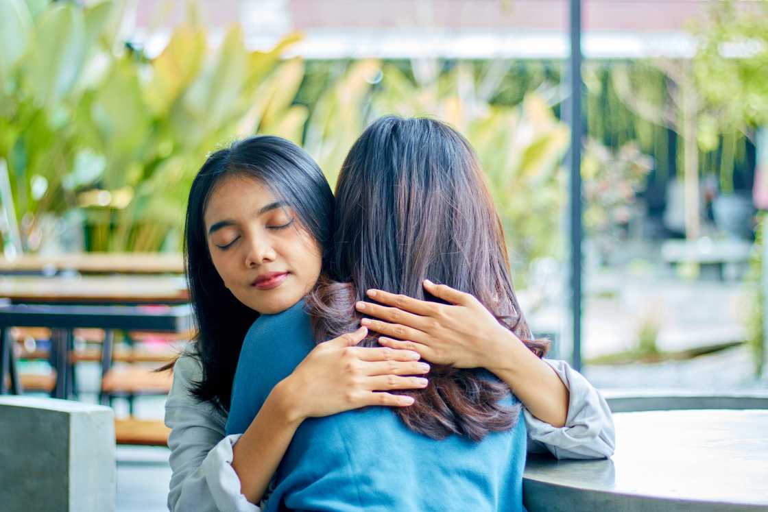 Two young women hugging in public Two young women hugging in public