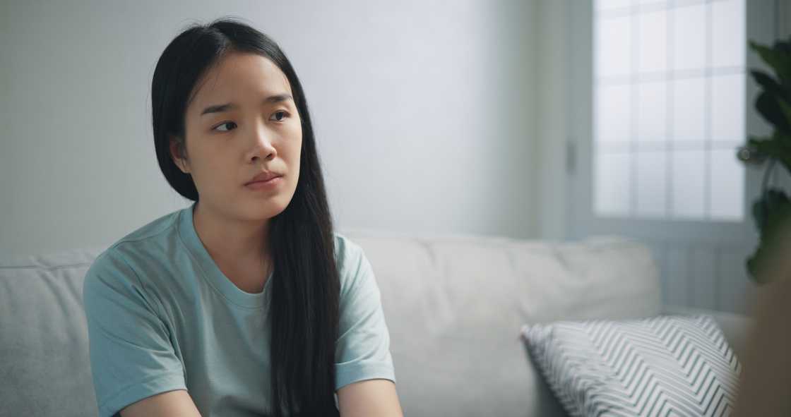 A young adult woman sitting on couch sulking A young adult woman sitting on couch sulking