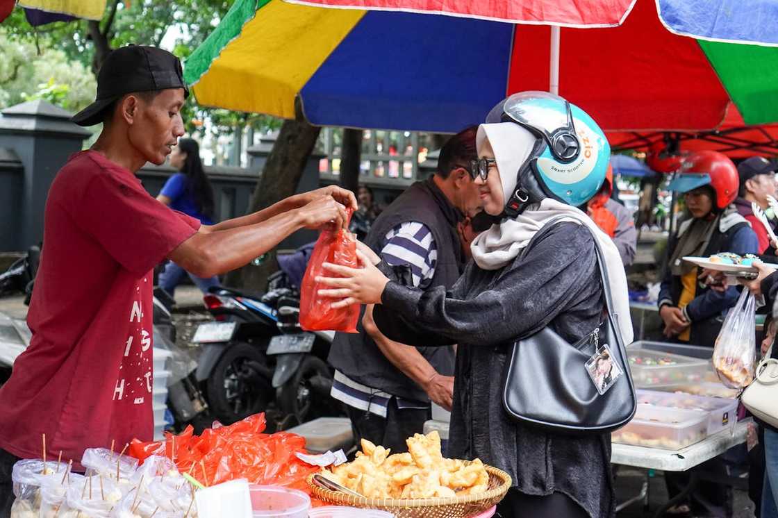 A street vendor completes a transaction with a female customer.