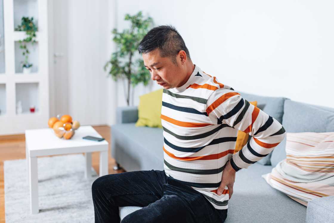 A man with a back pain at home A man with a back pain at home