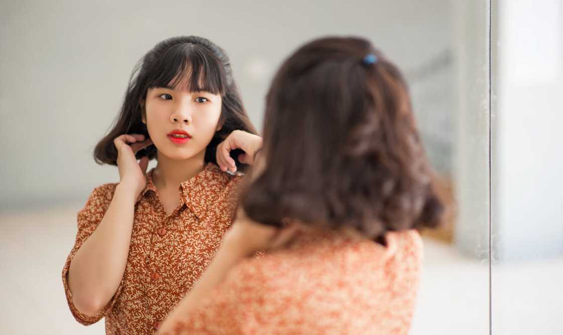 Woman staring at herself in a restaurant bathroom mirror.