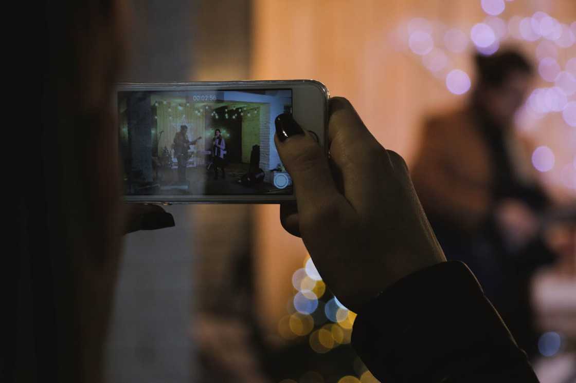 A person records a live performance on a smartphone. A person records a live performance on a smartphone.