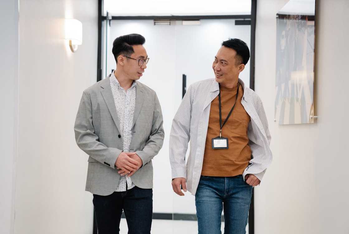 Two colleagues, walking down an office hallway, chatting and smiling. Two colleagues, walking down an office hallway, chatting and smiling.