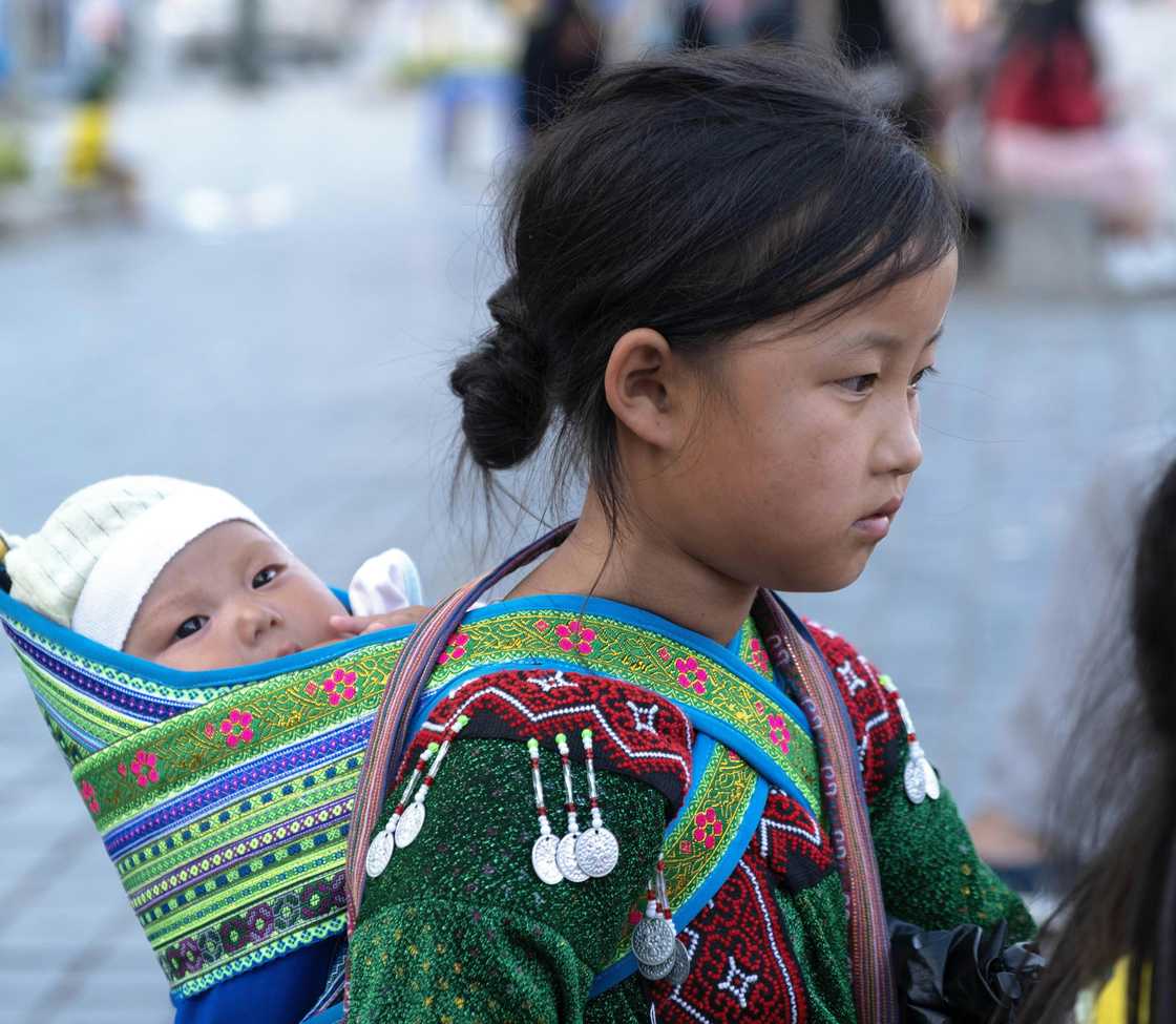 A young girl carrying a child on her back A young girl carrying a child on her back
