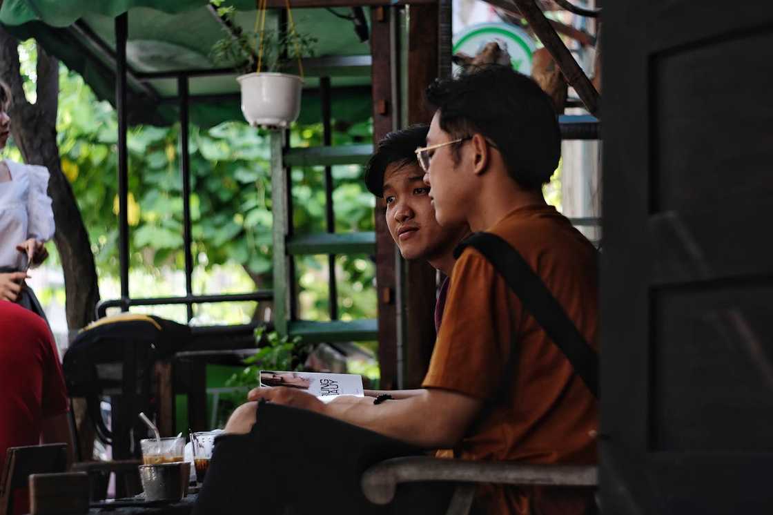 Two people smile and chat over drinks at a café table. Two people smile and chat over drinks at a café table.