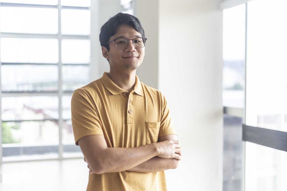 A man with glasses and yellow shirt smiling
