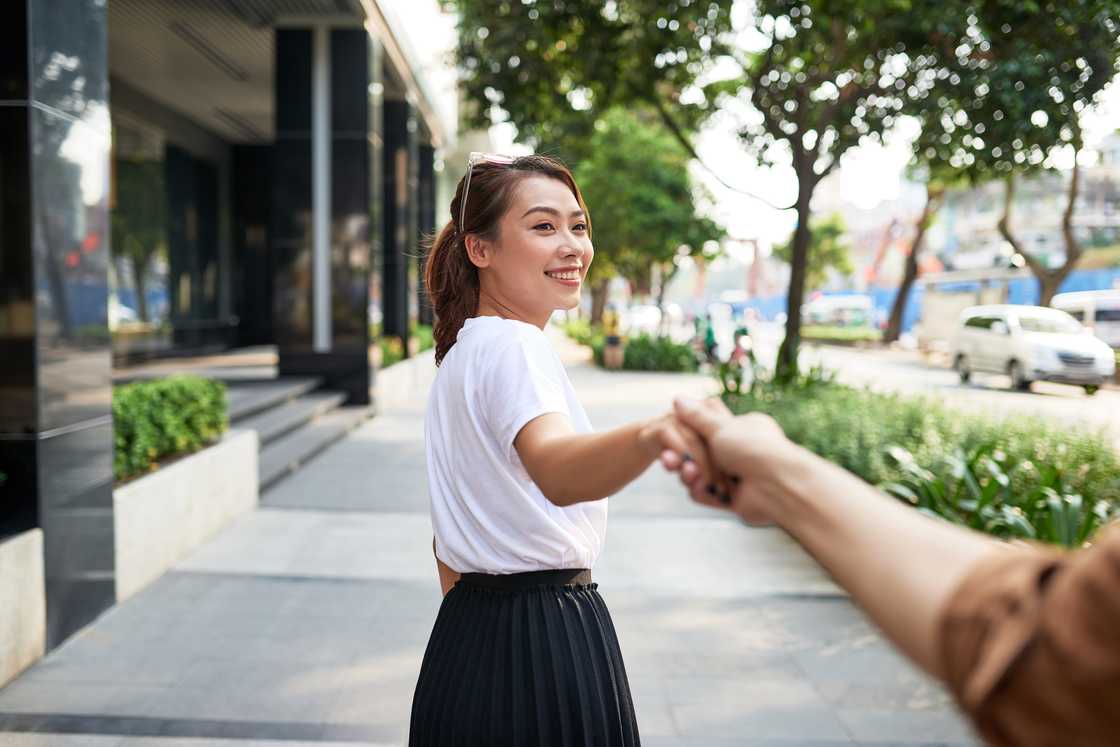 Young woman is holding her boyfriend's hand Young woman is holding her boyfriend's hand