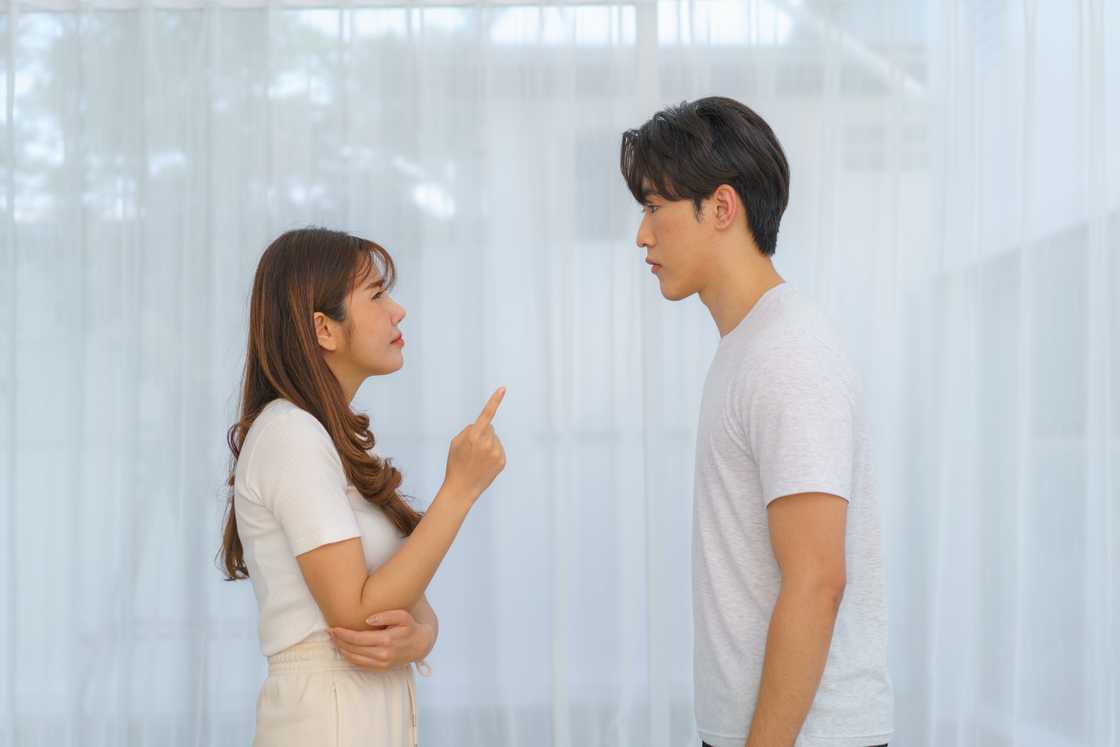 A woman points at her partner during a quarrel as he listens in silence A woman points at her partner during a quarrel as he listens in silence