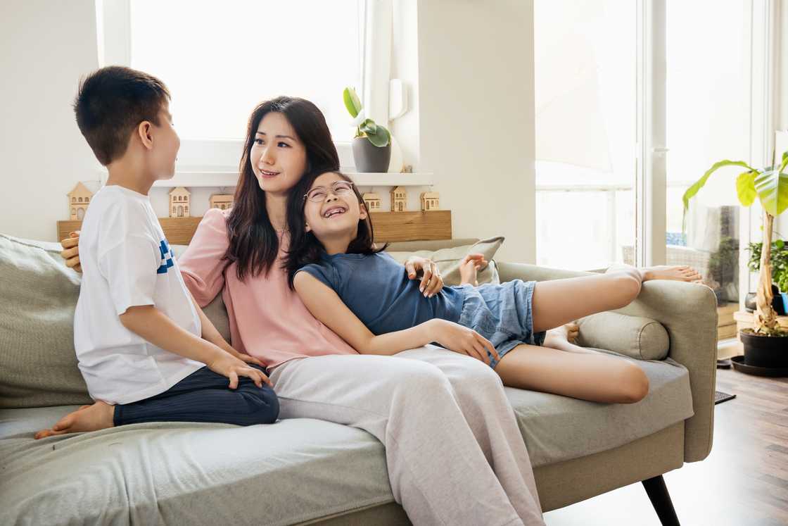 A mother sits embracing her two children