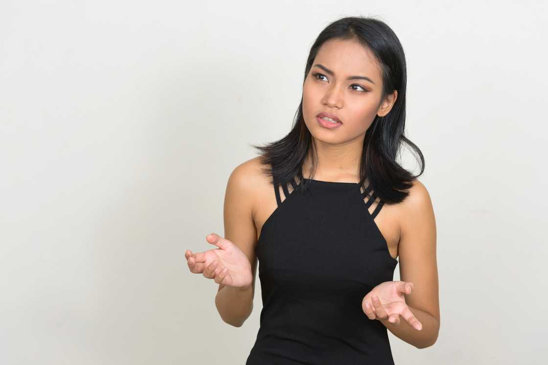 A disappointed young woman standing against a white background