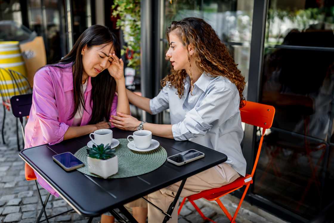 A lady is consoling her friend at a cafe
