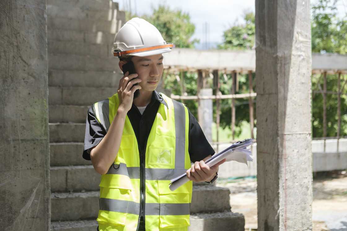 A construction worker with hardhat talking on mobile phone A construction worker with hardhat talking on mobile phone