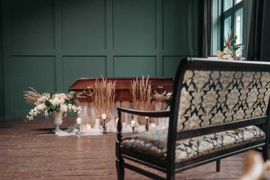 A closed wooden casket sits in a softly lit room.