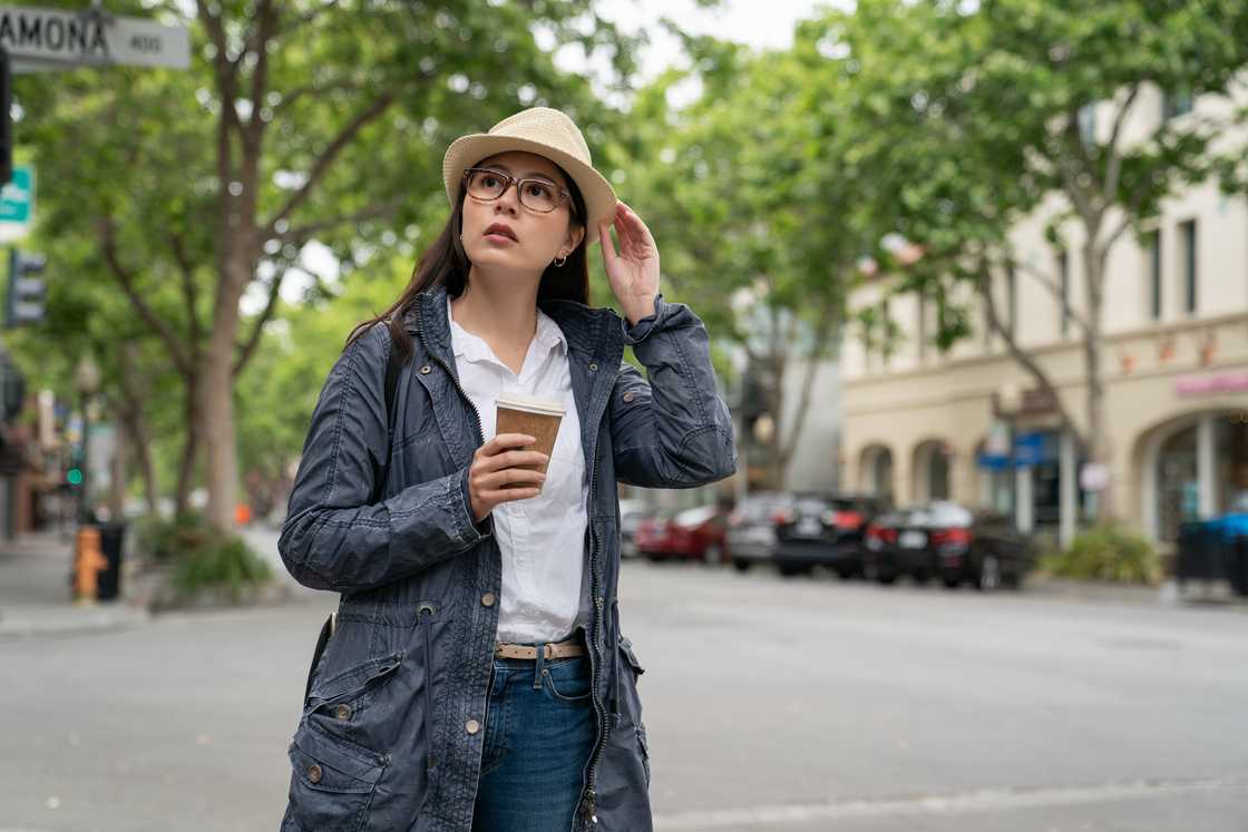 A lady holds a cup of coffee as she crosses the road A lady holds a cup of coffee as she crosses the road