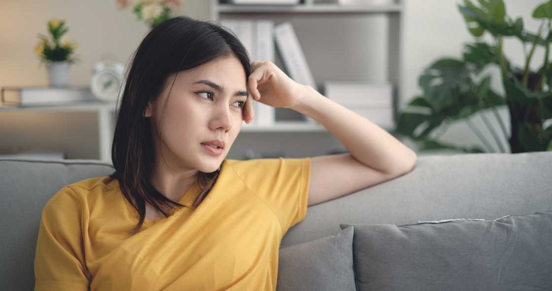 A young woman sitting on couch thinking