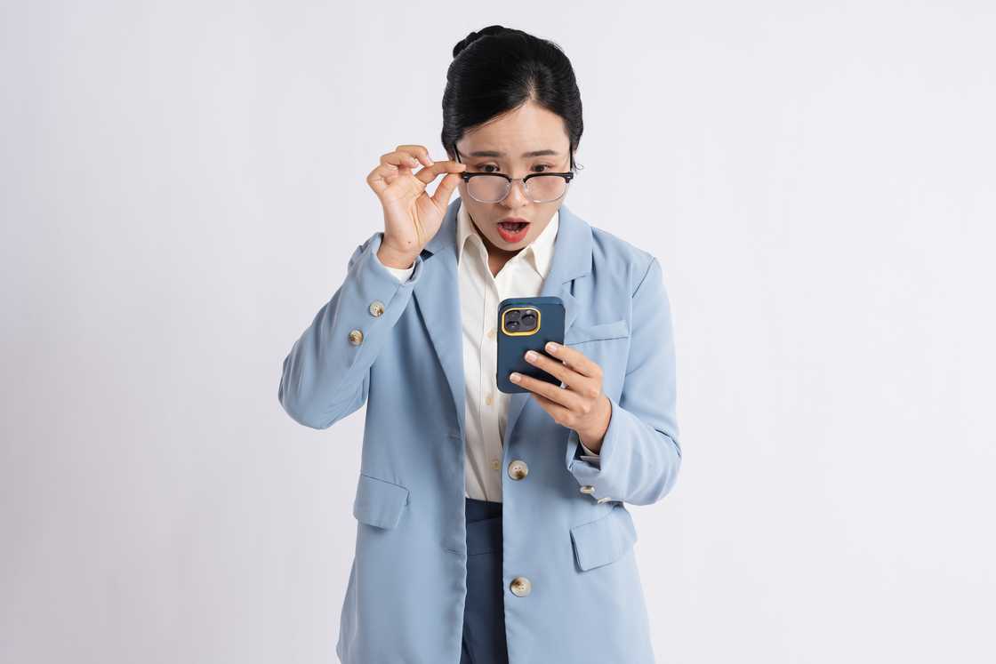 A woman is looking at her phone shocked