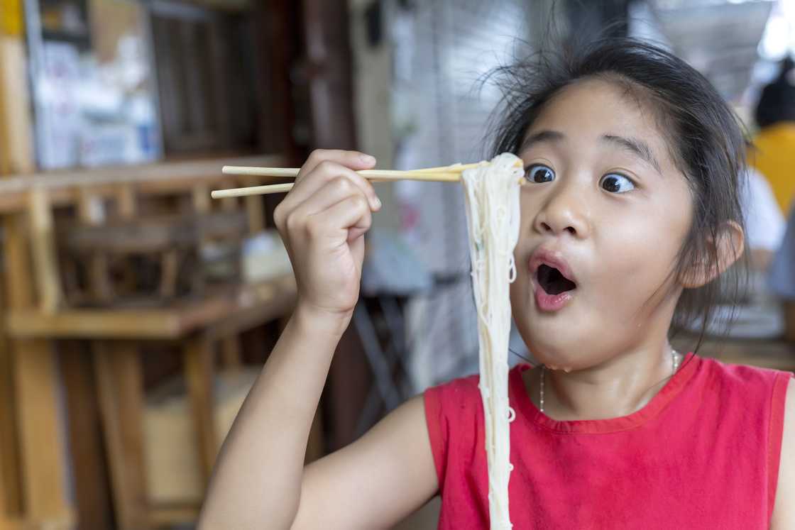 A little girl is eating noodles