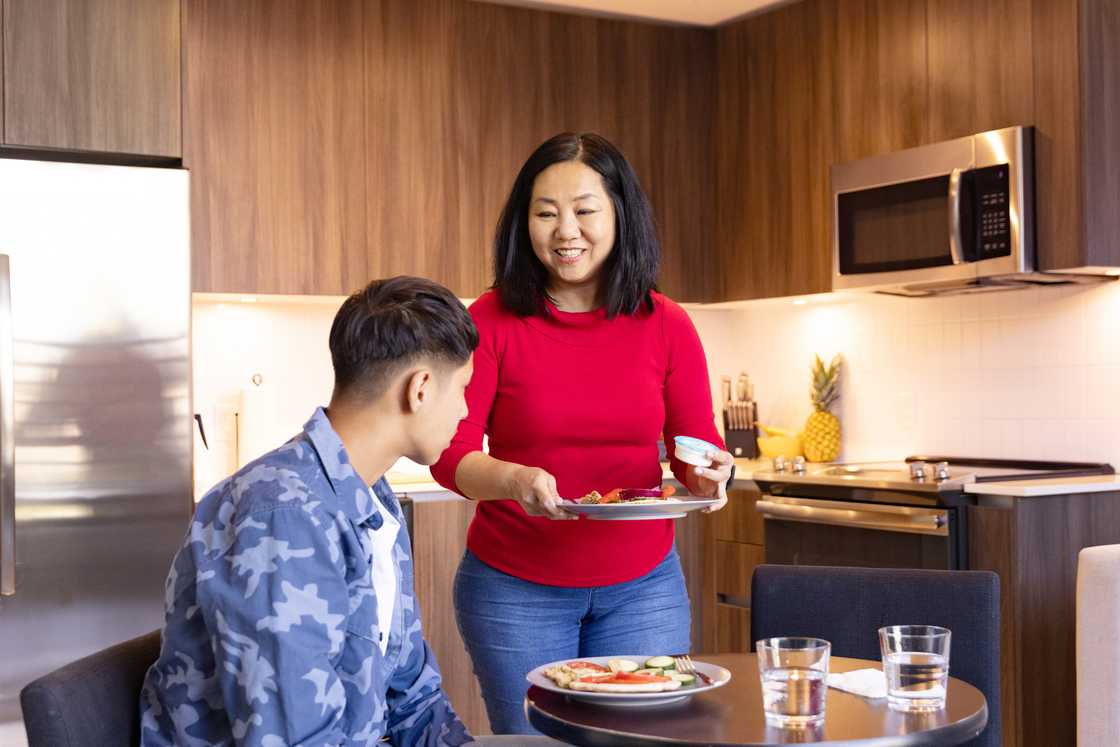 A mother and her teenage son sitting at the table for dinner