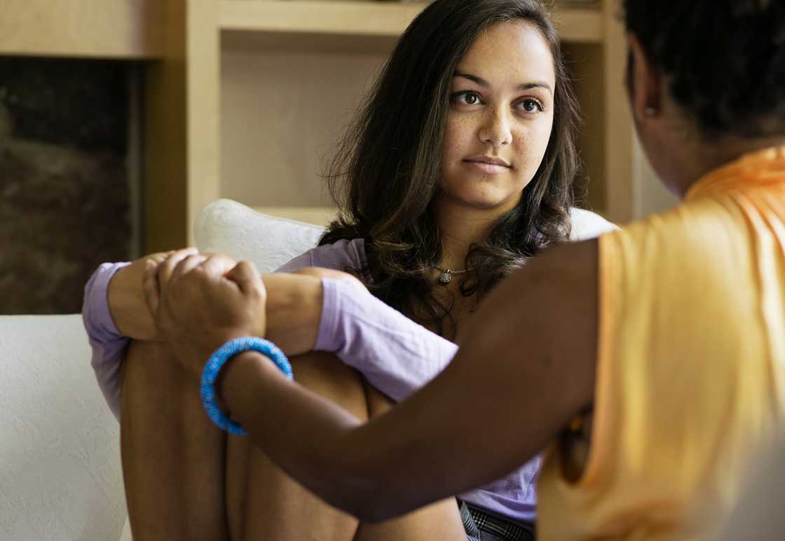 Two sisters talking while sitting on a sofa