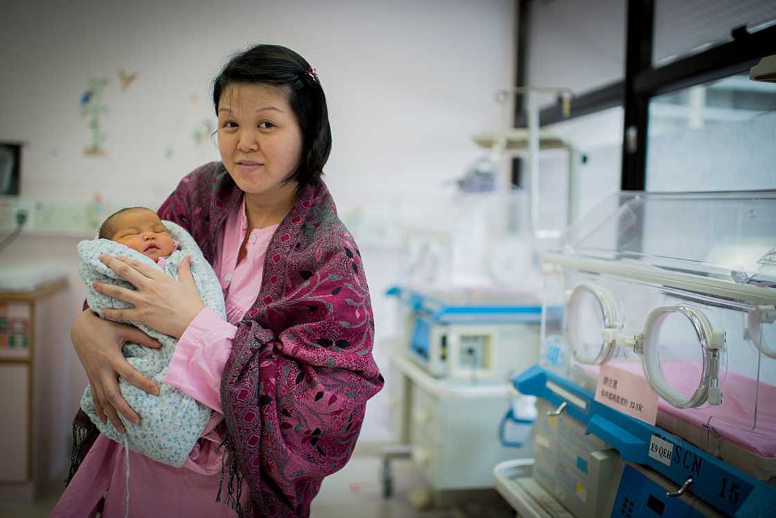 Filipino woman carrying her newborn baby at a hospital Filipino woman carrying her newborn baby at a hospital