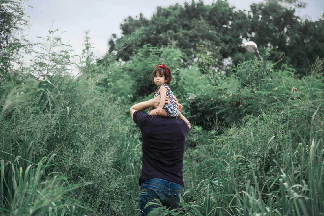 A father carrying his daughter in a forest A father carrying his daughter in a forest