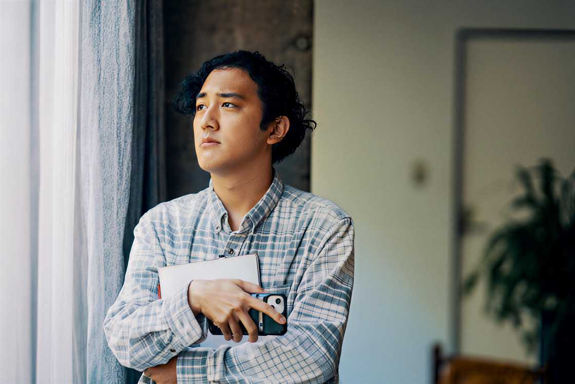 An adult male stands at the window An adult male stands at the window