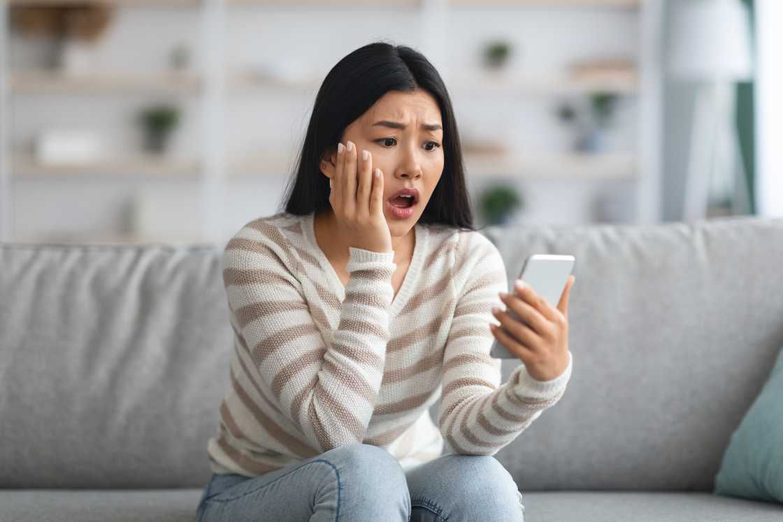 A shocked young woman looking at a mobile phone screen