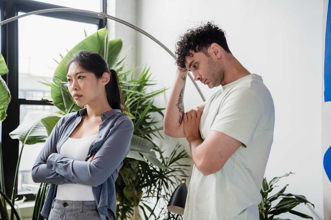 A couple argues indoors, both appearing tense in a bright room with plants.