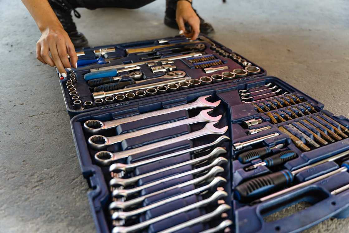 A person arranges tools inside an open mechanic’s toolkit.