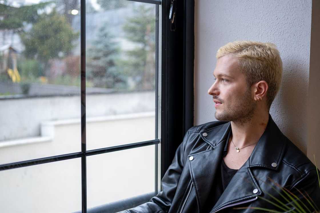 A thoughtful man looks out of a window.