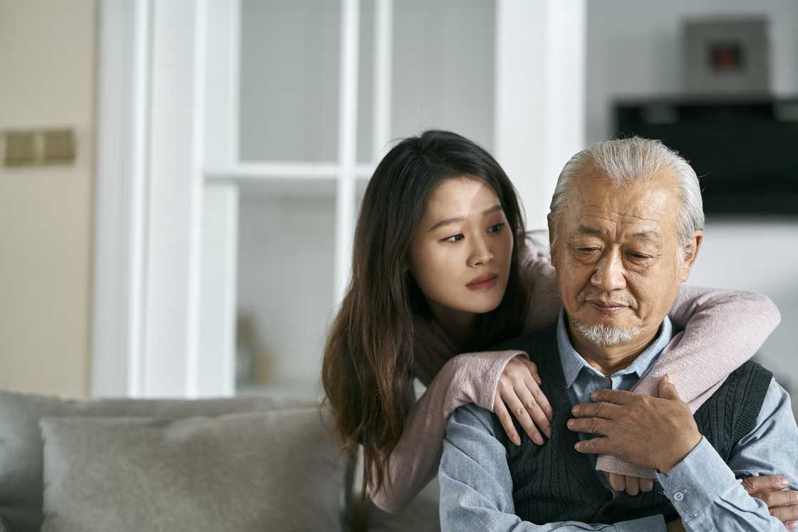 A granddaughter embracing her grandfather at home