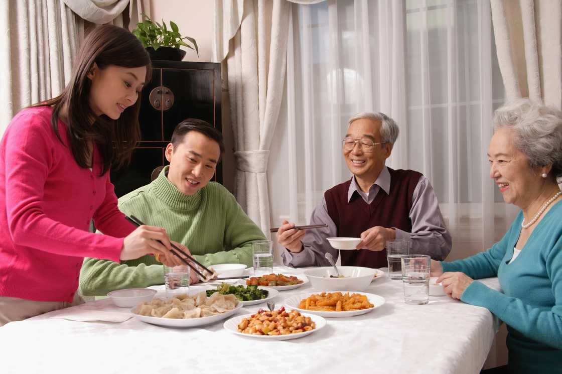A lady introduces her boyfriend to her family during dinner A lady introduces her boyfriend to her family during dinner