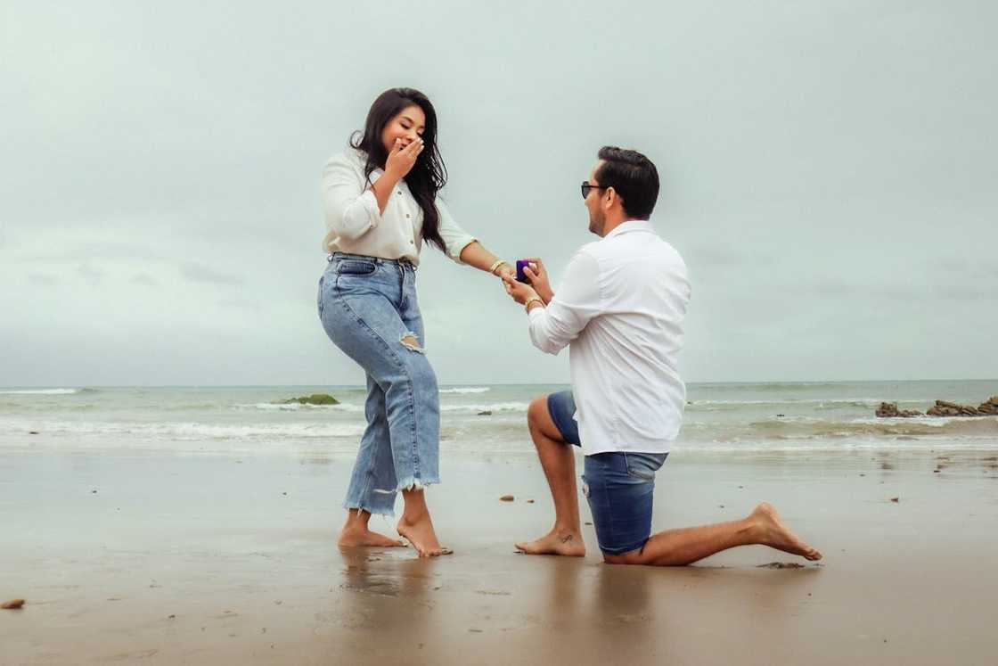 A man kneels on one knee while proposing to his girlfriend. A man kneels on one knee while proposing to his girlfriend.