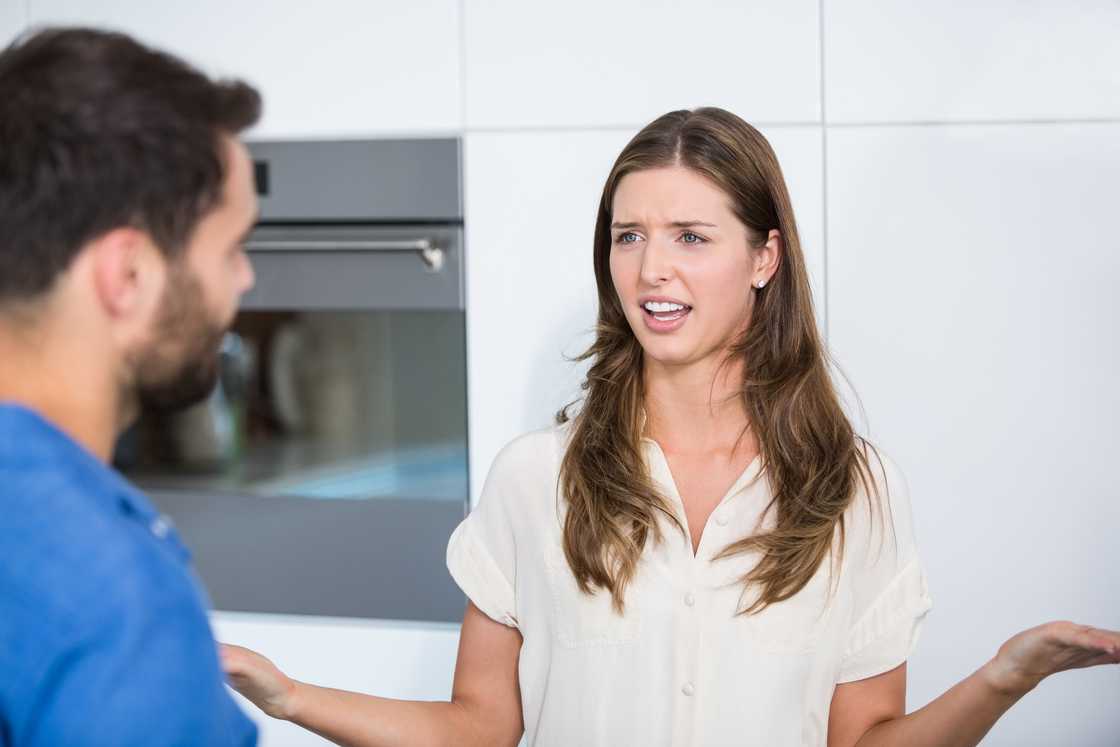 Young woman explaining to her husband in kitchen
